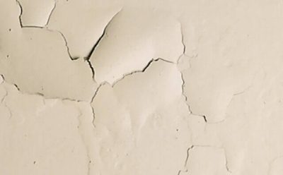 A sheet of cream colored paint with cracks from moisture.