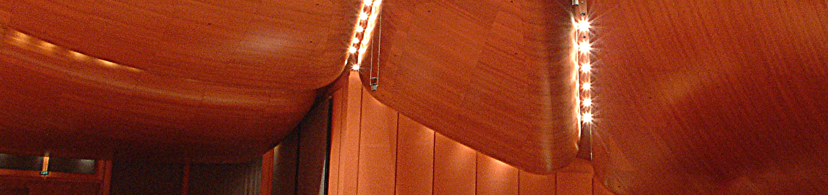 Empty auditorium with black chairs, wooden floors, and ceiling spotlights