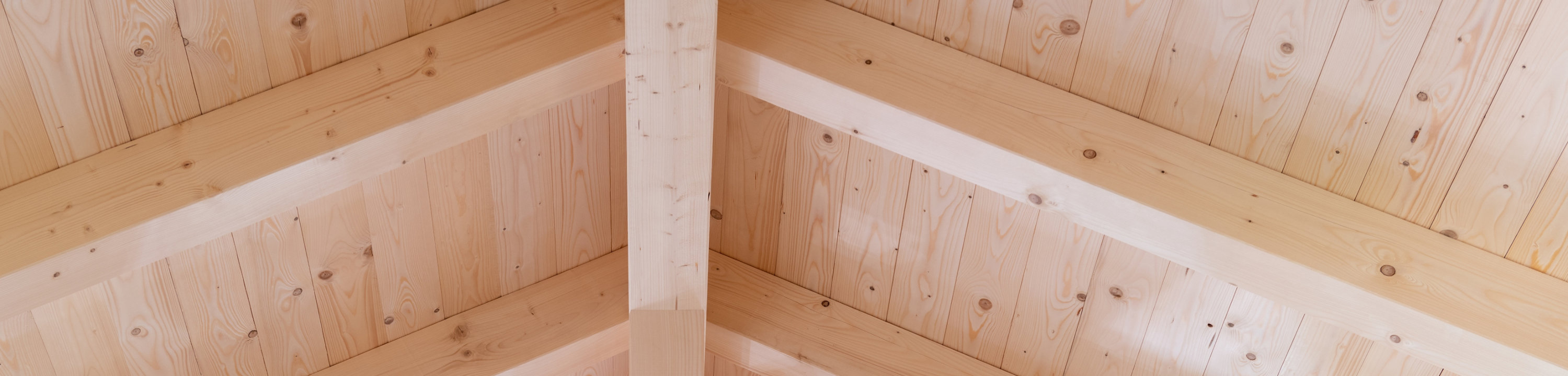 Wooden attic ceiling with exposed light-colored beams arranged in a triangular pattern. Sayerlack