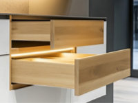 Open wood drawer in a modern kitchen unit, finished with coatings for backside panels and boards
