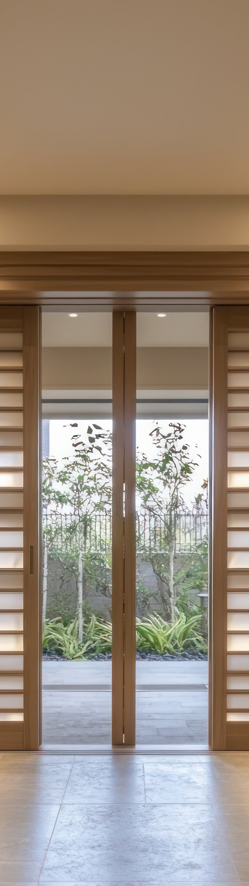 Bright hallway with tiled floor, natural wooden sliding doors with frosted glass, and decorative potted plant.