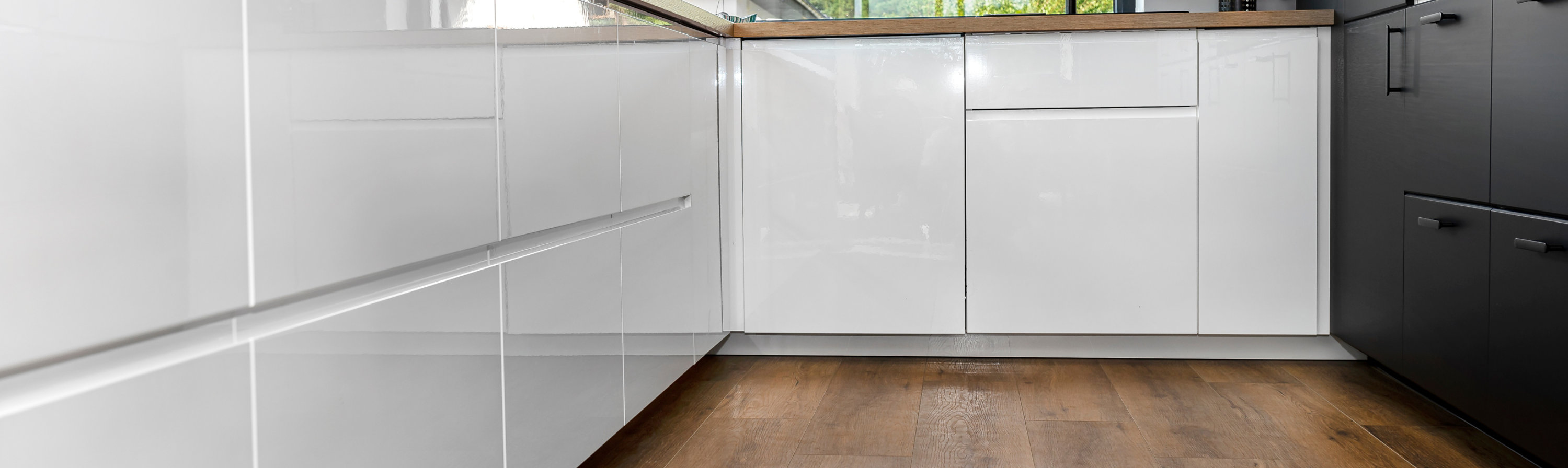 Modern kitchen with white cabinets, wooden countertops, and a pink orchid.