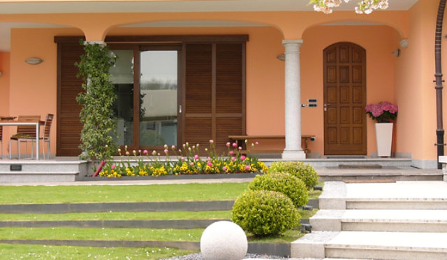 Front of a house with two large wooden windows and shutters.