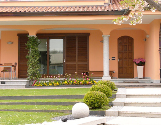 Front of a house with two large wooden windows and shutters.