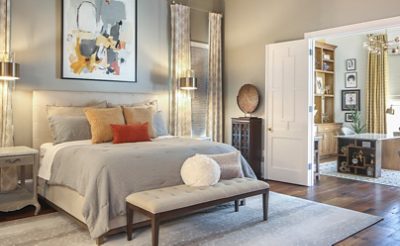 Inviting bedroom with adjoining home office space through open double doors with a neutral color scheme, unique artwork and furnishings.