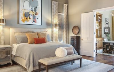 Inviting bedroom with adjoining home office space through open double doors with a neutral color scheme, unique artwork and furnishings.