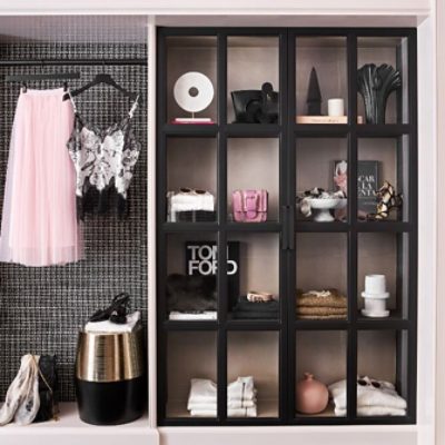 Detail shot of pink Chanel-inspired closet with neatly displayed clothes and accessories on black shelving.