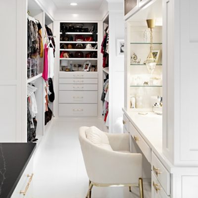 Vanity space in white walk-in closet with gold accents and recessed lighting.