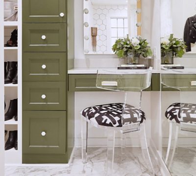 Tight shot of closet vanity area with olive green cabinetry and clear acrylic chair with graphic black and white seat cushion.