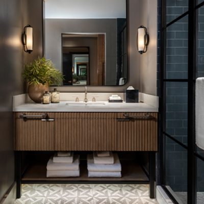 Guest bathroom vanity of Thompson Savannah hotel with large, round-edge rectangle mirror and moody lighting.