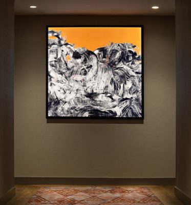Abstract artwork hanging on the dark taupe wall of the Canopy hotel corridor.
