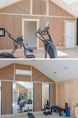 Modern fitness room with exercise equipment, wooden slat walls, Sherwin-Williams Anchors Aweigh accent wall, and large windows.