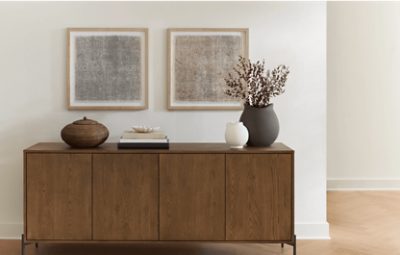 Walls painted in SW 7012 Creamy, wooden credenza with minimal decor on top and 2 paintings above it.