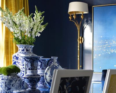 Blue and white porcelain vases with flowers, next to a gold lamp and a blue gradient painting with walls painted Gale Force by Sherwin-Williams. 