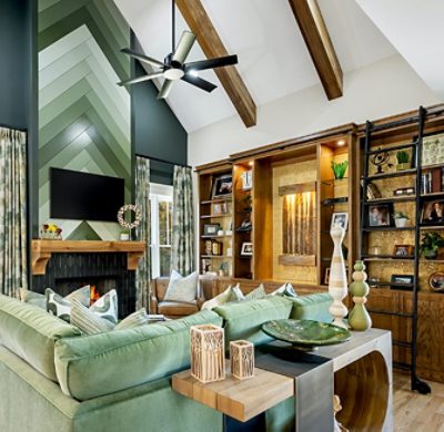 A modern living room with a green-accented fireplace, green sectional sofa, wooden shelves, and vaulted ceiling with wooden beams. 