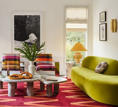 A colorful, modern living room with a lime green sofa, plaid chairs, and a red patterned carpet, featuring eclectic decorations against a backdrop of White Snow painted walls. 