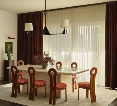 Modern dining room with a stone table, wooden chairs with circular backrests, and a geometric chandelier within walls painted White Snow. 