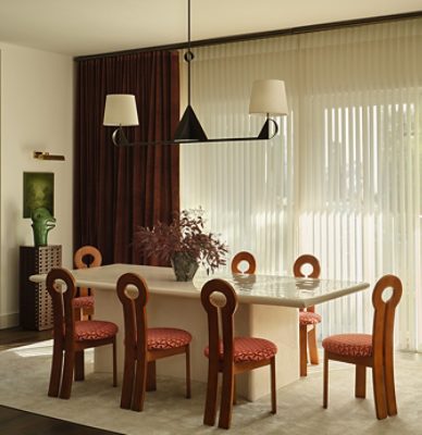 Modern dining room with a stone table, wooden chairs with circular backrests, and a geometric chandelier within walls painted White Snow. 