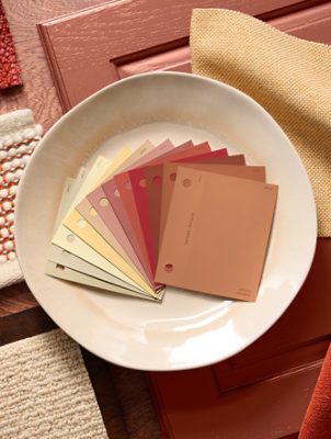 An arrangement of design materials featuring color swatches, fabric samples, and textured items in warm earth tones on a wooden surface. 