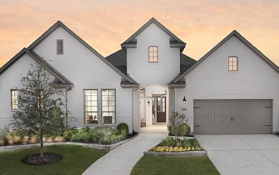 Street view of new home painted white with steep gables, attached garage, and lush landscaping at sunset.
