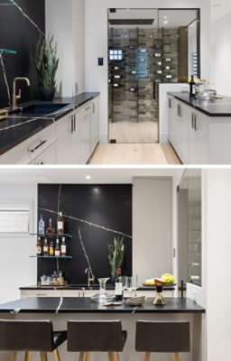 Home bar area with white walls and cabinets and dark countertops with adjacent glass-walled wine storage room.