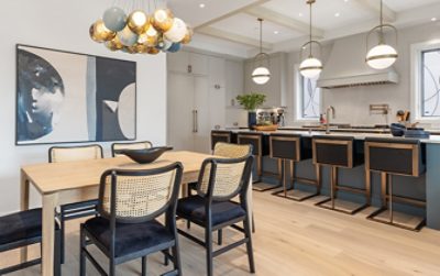 Open concept kitchen and dining area with modern light fixtures, leaded glass, and blue-green island.