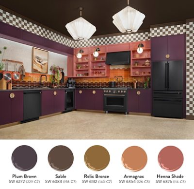 A modern kitchen staged at KBIS with plum cabinets, coral shelving, and orange backsplash, featuring black Cafe Appliances refrigerator and stove, and accented with large pendant lights. Swatches of similar paint colors from Colormix 2026: Plum Brown, Sable, Relic Bronze, Armagnac, Henna Shade.