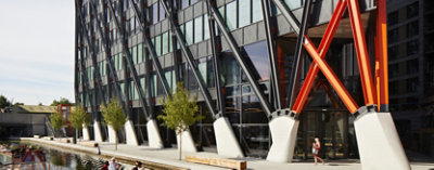 Exterior of the Brunel Building shown close up at ground level, where the supports of the steelwork exoskeleton can be seen reaching up to the rest of the structure, out of frame.