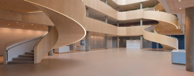 Interior atrium of Denmark psychiatric hospital in a soft, light neutral color scheme and with sweeping spiral staircases lit from beneath.