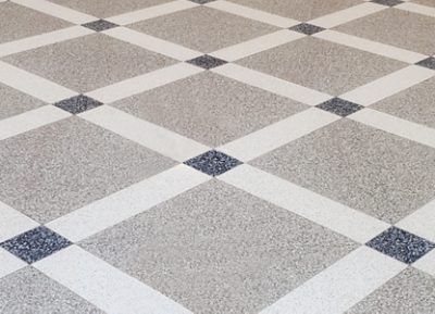 A patterned floor with gray, navy and white terrazzo poured in a square tile pattern forming a diagonal grid. 