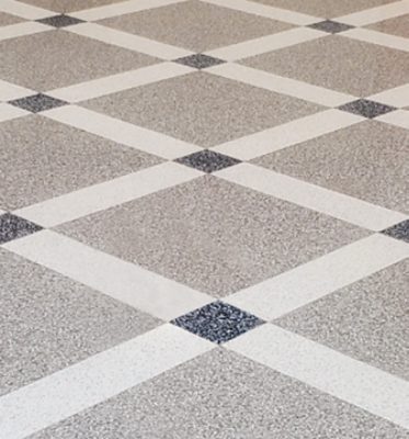 A patterned floor with gray, navy and white terrazzo poured in a square tile pattern forming a diagonal grid. 
