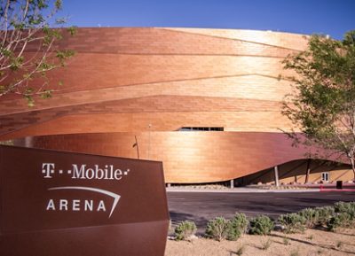 Exterior view of the T-Mobile Arena with copper-colored panels and a sign in the foreground. 