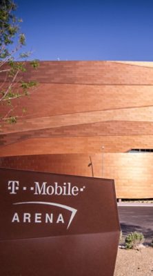 Exterior view of the T-Mobile Arena with copper-colored panels and a sign in the foreground. 