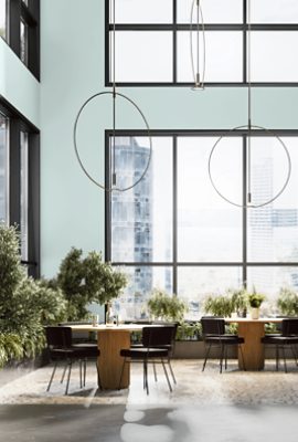 An atrium with tables and chairs among green plants with walls painted Tidewater SW6477.