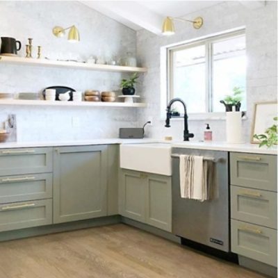 A modern kitchen with floating shelving and Sherwin-Williams 2022 color of the year, Evergreen Fog, painted on the lower cabinets.