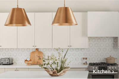 A white  kitchen with a geometric backsplash and two gold pendants over the island.