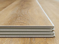 Layered laminate flooring planks with visible edge detail and multi-layer structure, highlighting the protective surface finish