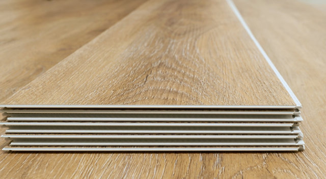 Layered laminate flooring planks with visible edge detail and multi-layer structure, highlighting the protective surface finish.