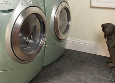 A laundry room with a new light green washer and dryer, dog statue and tile flooring.