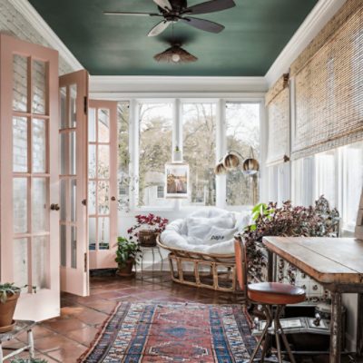 A bright sunroom with the ceiling painted Billard Green sw 0016, a white brick accent wall, bright white trim, and glass paneled French doors painted Jazz Age coral sw 0058.