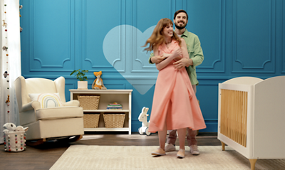 Two people dancing in a nursery with a blue accent wall.