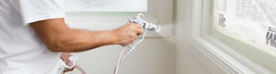 A person painting window sills with a sprayer.