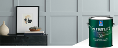 A wall painted light gray with a black side table with decor and a can of Emerald interior paint.