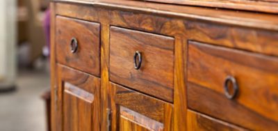 Close-up of a dark-stained wooden dresser, highlighting the rich color and smooth finish of the wood.