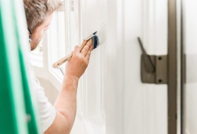 Person Painting walls white with a Brush.