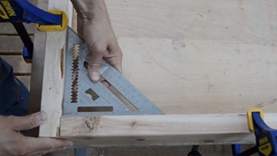 A man measuring a right angle for cutting wood.