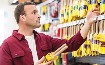 A man choosing a Sherwin-Williams paint brush in a store. 