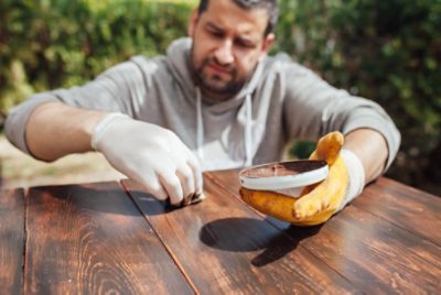 A person applying stain to a wood table with a rag.