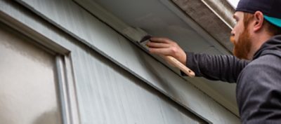 A man painting the side of a house