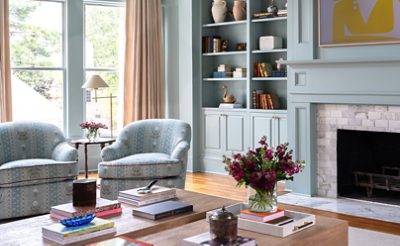 Light blue-green painted living room with matching round back arm chairs near tiled fireplace.